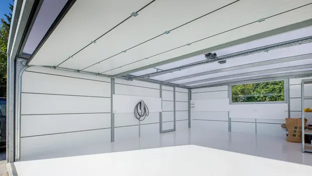 Kig indendørs i en UNA garage med Isopanel og vindue med udsigt mod haven