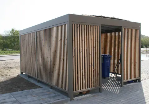 UNA containerskjul pulverlakeret og med lamelbeklædning og sedumtag